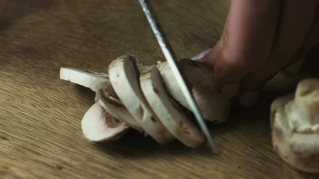 Slicing raw mushrooms on a cutting board closeup