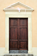 Portale di ingresso ligneo della Chiesa San Filippo Neri a Fara in Sabina, che si ipotizza già costruita dal 1685. Foto verticale.  Visione frontale.