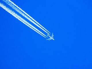 Airplane with chemtrails on blue sky