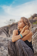 Fototapeta premium beautiful young woman sitting on the rocks, outdoor.