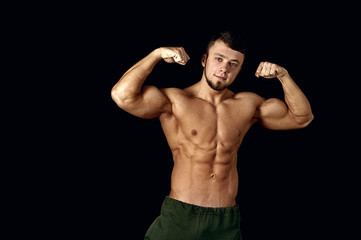 Fototapeta na wymiar young muscular man showing his body on a dark background