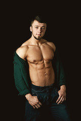 young muscular man showing his body on a dark background