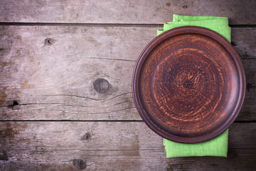 Table setting. Brown plate on green napkin on vintage wooden bac