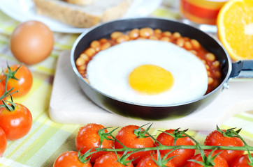 Fried egg with beans, toast bread, fresh juice, tomatoes and oranges