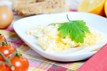 Scrambled eggs, toast bread, fresh juice, tomatoes and oranges