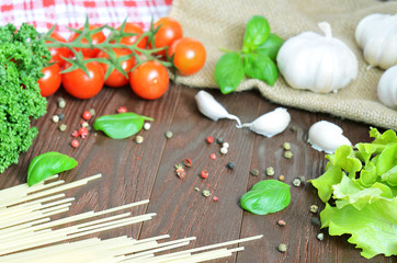 Tomatoes, spaghetti (pasta), parsley and garlic on wooden table