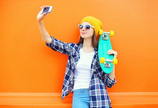 Pretty cool girl in sunglasses with skateboard taking picture se