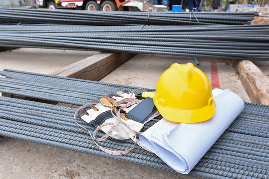 Yellow safety helmet and blueprints with rebar at the constructi