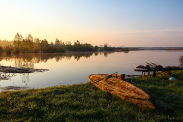 Fishing boat with fishermen gear lies on the banks of the river in the early morning fog