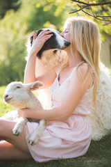 Farm life. Blonde farmer woman playing with Borzoi dog and baby lamb. Living with animals.