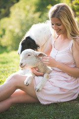 Farm life. Blonde farmer woman playing with Borzoi dog and baby lamb.