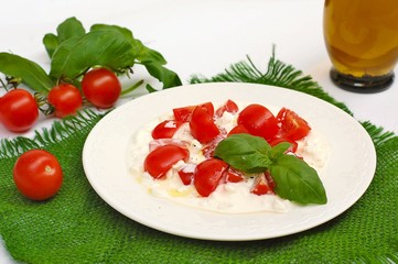 Salad from cherry tomatoes and cottage cheese with basil and olive oil