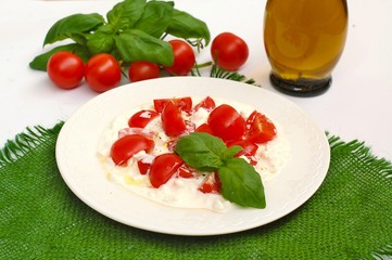 Salad from cherry tomatoes and cottage cheese with basil and olive oil