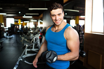 Fototapeta premium Muscular bodybuilder guy doing exercises with dumbbells.Strong Athletic Man Fitness Model Torso showing six pack abs.Strong Athletic Man Fitness Model Torso showing big muscles