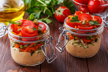 Healthy breakfast - hummus with vegetables in glass jars.