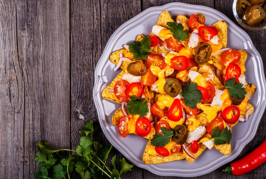 Nachos with melted cheese sauce, jalapeno, chicken and vegetable