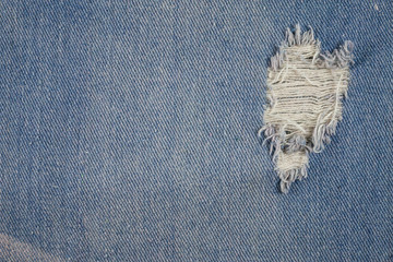 Blue jeans background closeup view to torn texture.