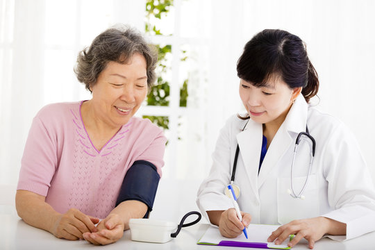 nurse checking senior woman blood pressure