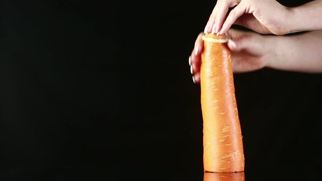 Orange carrot with a condom on a black background