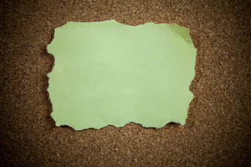Crumpled yellow sticky note on cork board.