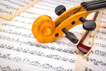 Close view of violin scroll and bow on score