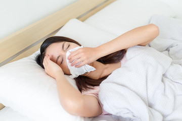 Sick Woman sneezing into Tissue
