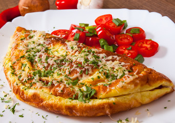 omelette with cheese and salad in a plate on wooden table