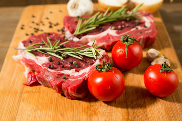 Raw beef steak on  wooden table with vegetables