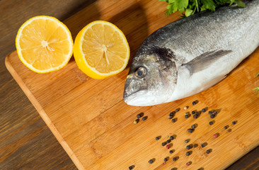 Fresh uncooked dorado or sea bream fish with lemon