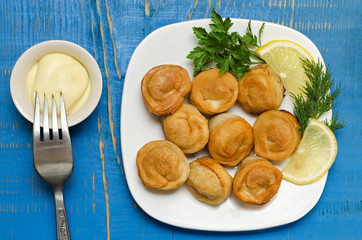 Fried dumplings on the plate with mayonnaise, herbs and lemon.