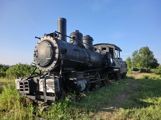 Obraz na płótnie Canvas Vintage old antique train locomotive engine perspective in sun - landscape color photo