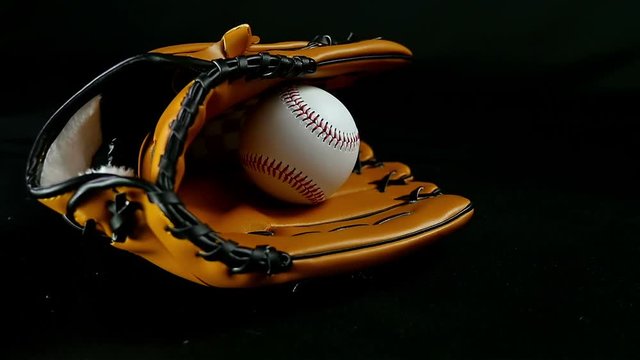Baseball glove and ball on a black background, slow motion