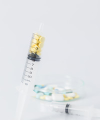 closeup of syringe with spoon on many pills and capsules for hea