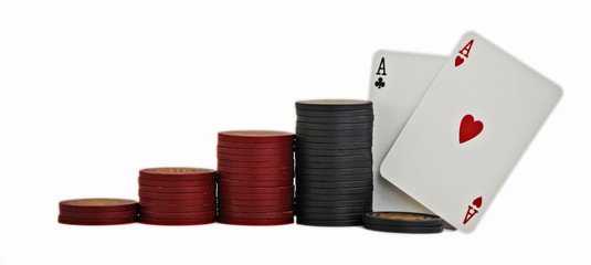 Studio shot of a pair of aces with red and black poker chips, stacked in ascending order, on white background.