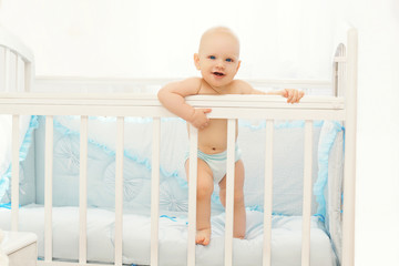 Little baby standing on the bed at home in room
