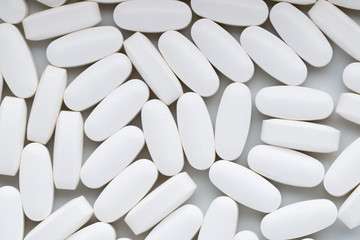 Fototapeta na wymiar White pills on the white background.