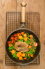 pork neck steak with peas and carrots in a cast iron pan