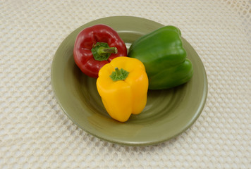 Green, red and green peppers on plate on tablecloth