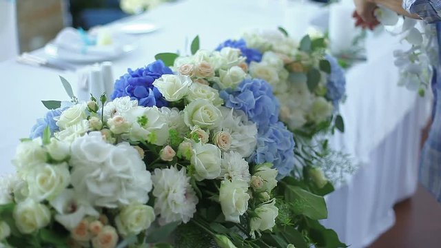 a woman's hands fixing the flowers in the bouquet. a florist creates a bouquet of hydrangeas, roses and orchids for festive decoration wedding