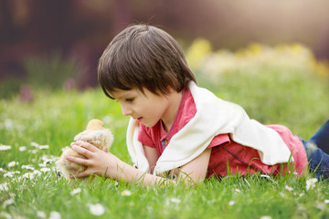 Sweet little child, preschool boy, lying on the grass, playing w