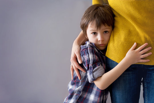 Sad little child, boy, hugging his mother at home