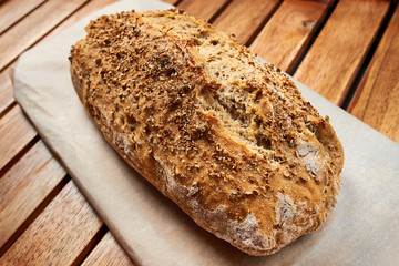 Loaf of homemade bread whit coriander seeds on wooden background