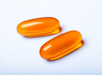 macro photo of two orange pills isolated on white background
