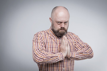 Obraz premium The bearded middle-aged man praying with hands folded, with an a