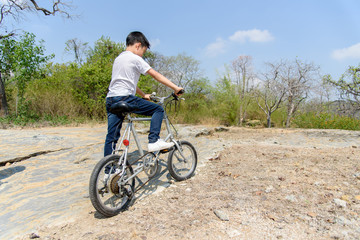Obraz premium Little boy ride bicycle on the rock road.