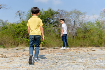 Two Boy walking on the rocky land.