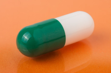 white and green pills on orange background close up macro