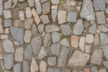 Old stone paving on the street. Detail of historic granite tiles.
