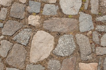 Old stone paving on the street. Detail of historic granite tiles.
