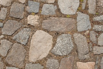 Old stone paving on the street. Detail of historic granite tiles.
